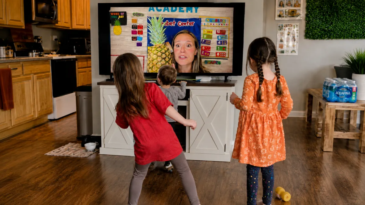 Kids moving with the teacher on a large screen TV