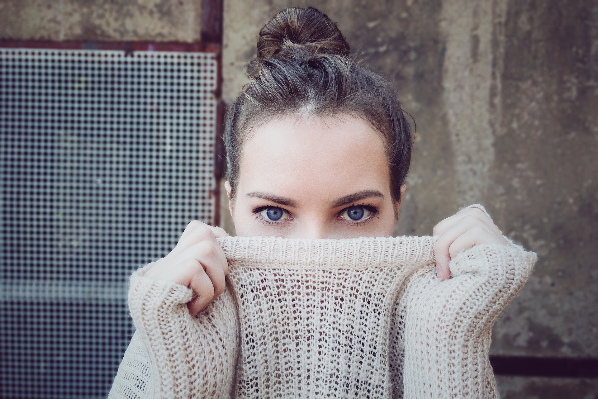 A photo of a women in fawn response hiding behind her jumper