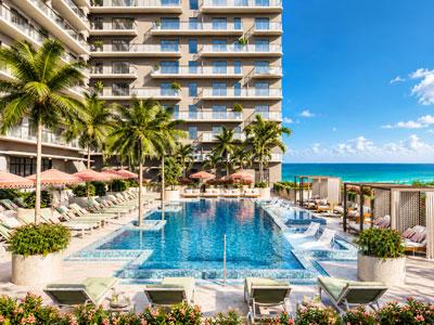 Piscina de lujo de NoBe PARC en Miami Beach, Florida, con vista al océano, cabañas privadas, tumbonas y áreas de descanso rodeadas de palmeras.