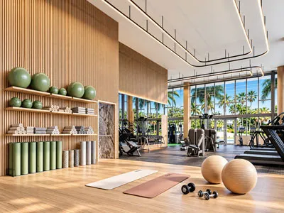 Moderno gimnasio de NoBe PARC en Miami Beach, Florida, equipado con máquinas de ejercicio, área de yoga, pesas y amplios ventanales con vistas tropicales