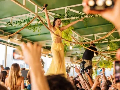 Artista animando una fiesta con música en vivo y público celebrando en un ambiente tropical, representando el entretenimiento y estilo de vida de Miami.
