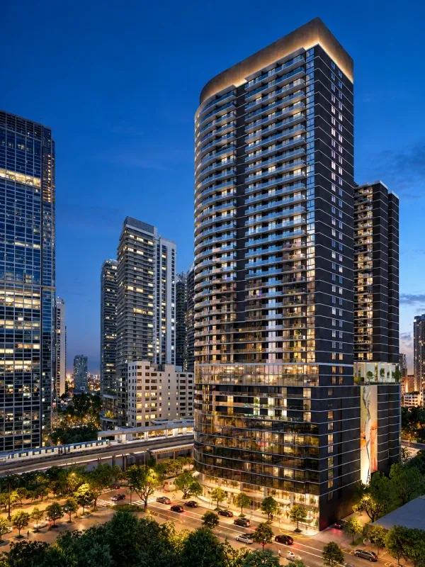 Vista al atardecer de One Twenty Brickell Signature Residences, torre de residencias de lujo en Brickell, Miami, con balcones modernos, fachada iluminada y rascacielos alrededor.