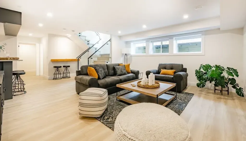 Beautiful renovated Myrtle Beach basement with modern design, hardwood floors, cozy sofa, mini bar, coastal decor and natural light