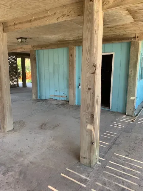 Cleared driveway with partially demolished garage, debris swept aside, exposed beams, lawn, and blue sky showcase professional demolition in Myrtle Beach