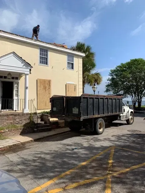 Demolition site in Myrtle Beach SC with cleared lot, stacked debris, excavator, and clear blue sky, showcasing safety and precision.