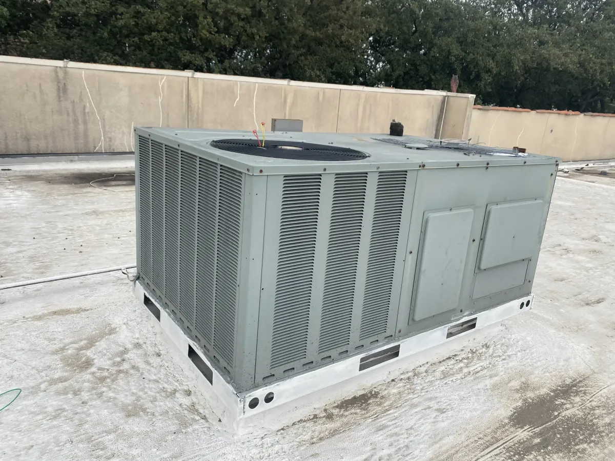 Repaired commercial HVAC unit outside modern industrial building in Poolville Texas with landscaped surroundings under bright sunlight