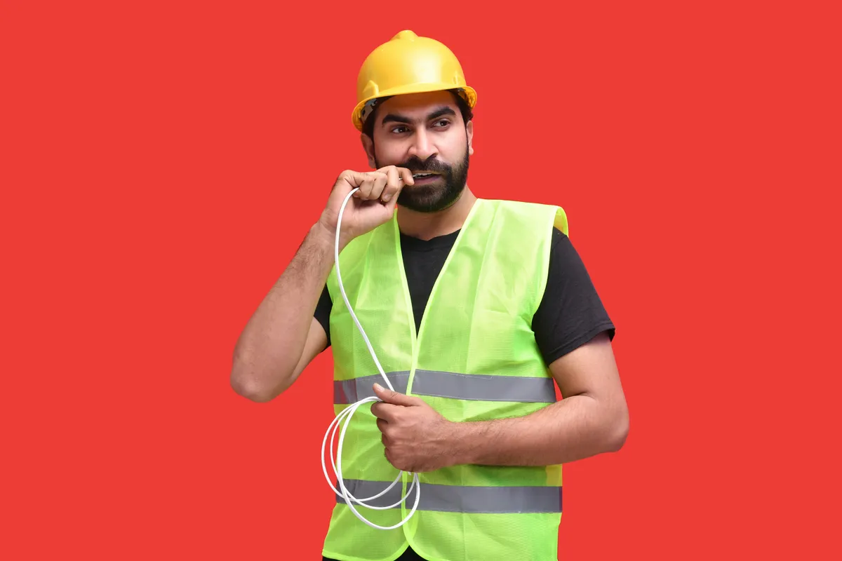 Tradesperson in a hard hat and high-visibility vest talking on the phone