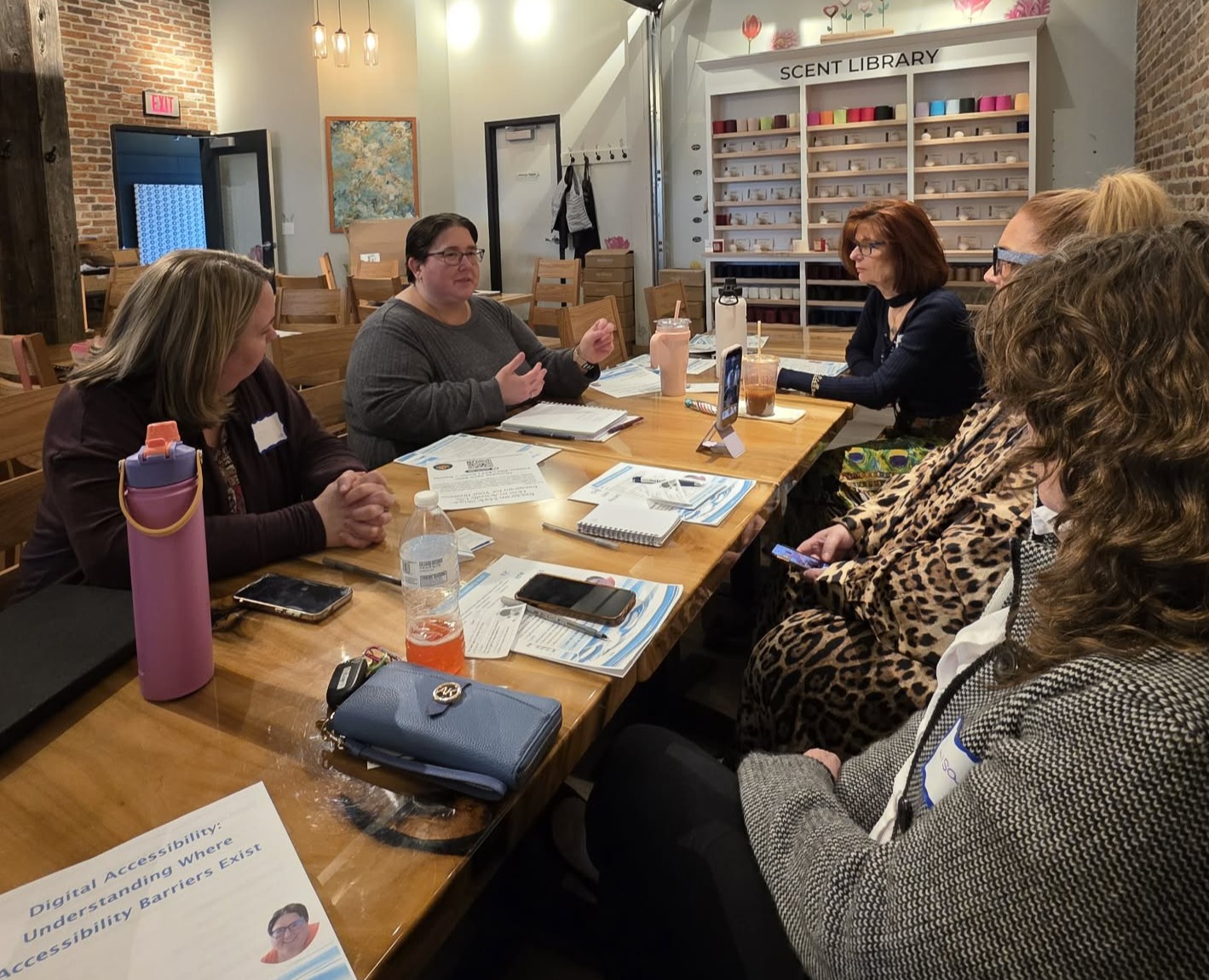 Jenn Davey provides explanation to four women seated around a table.