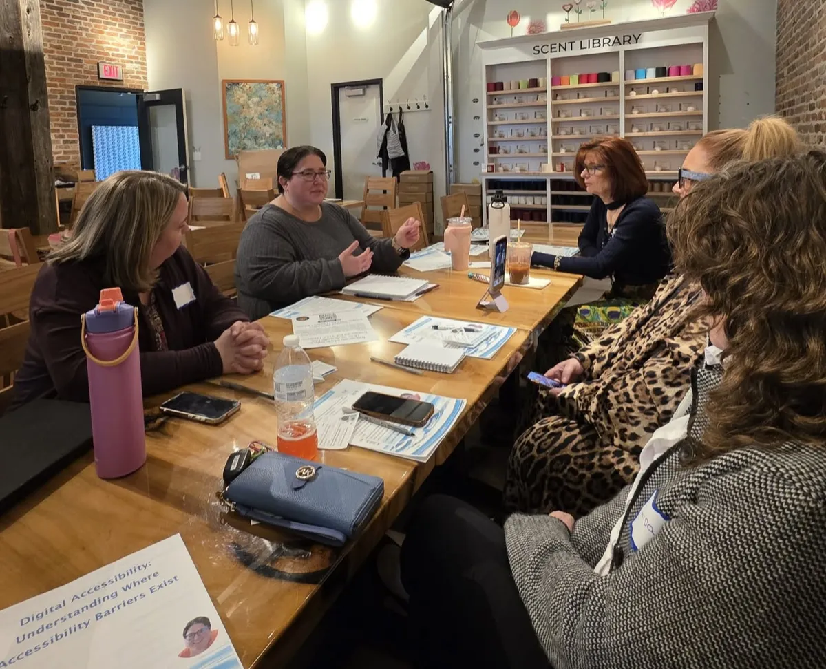 Jenn Davey provides explanation to four women seated around a table. 