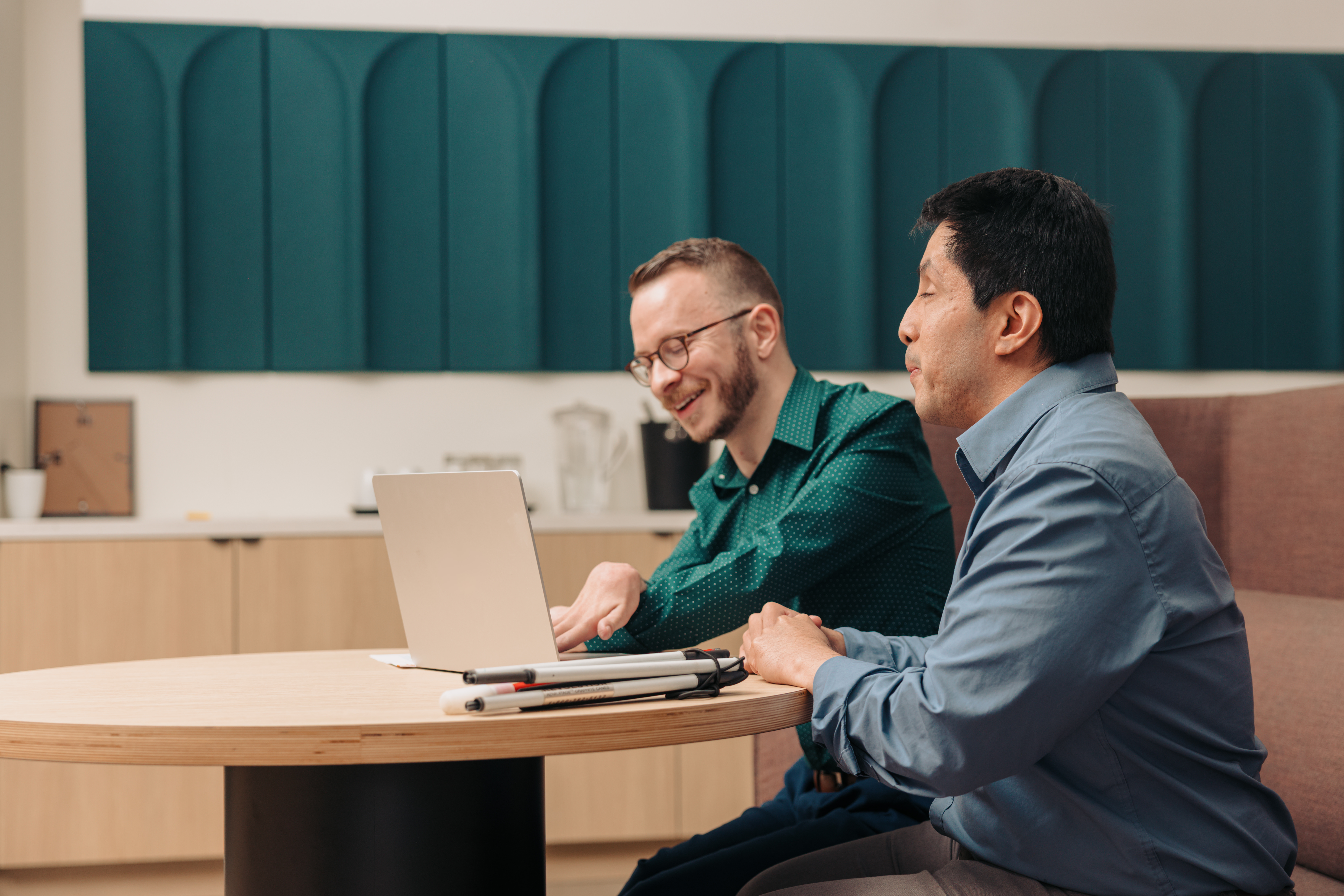 Two professionals collaborating at a laptop while discussing digital content and accessibility.