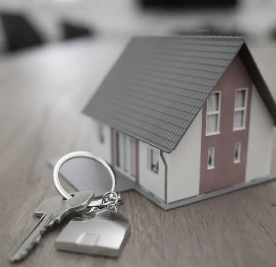 House key with small model home on desk symbolizing property management and restoration partnership in Sydney.