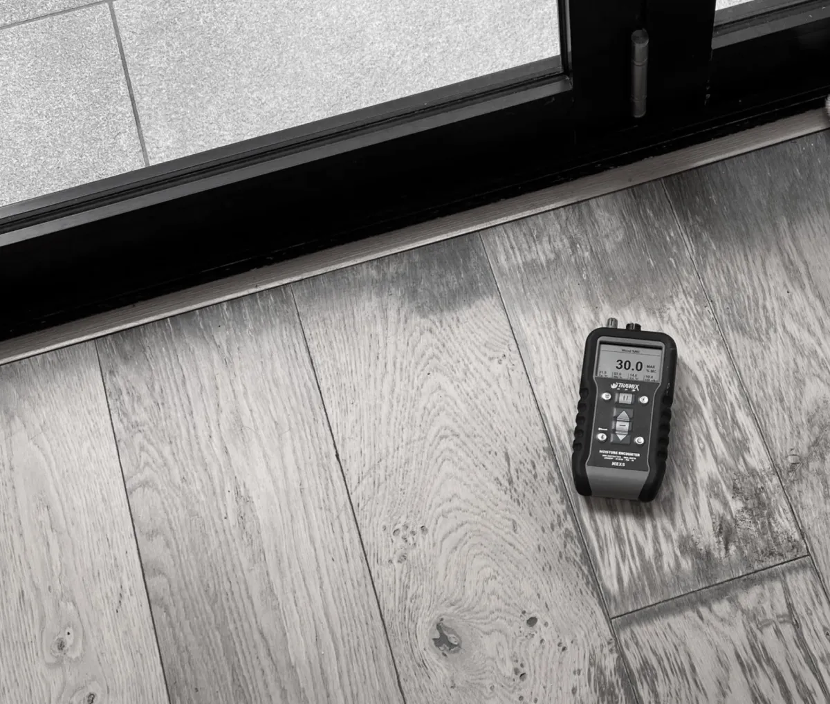 Moisture meter testing timber floor after flood damage during restoration service in Sydney.