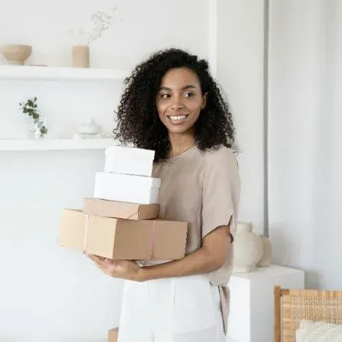 Smiling woman holding moving boxes inside a bright modern home.