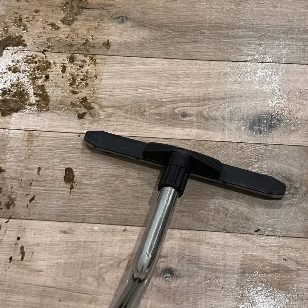 Technician cleaning contaminated floor with extraction tool after sewer backup.