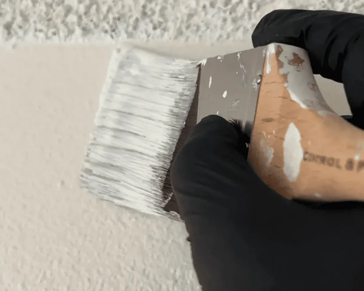 Worker repainting interior wall with mould-resistant paint after remediation.