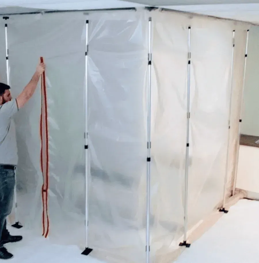 Technician setting up plastic containment barrier for bathroom mould removal.