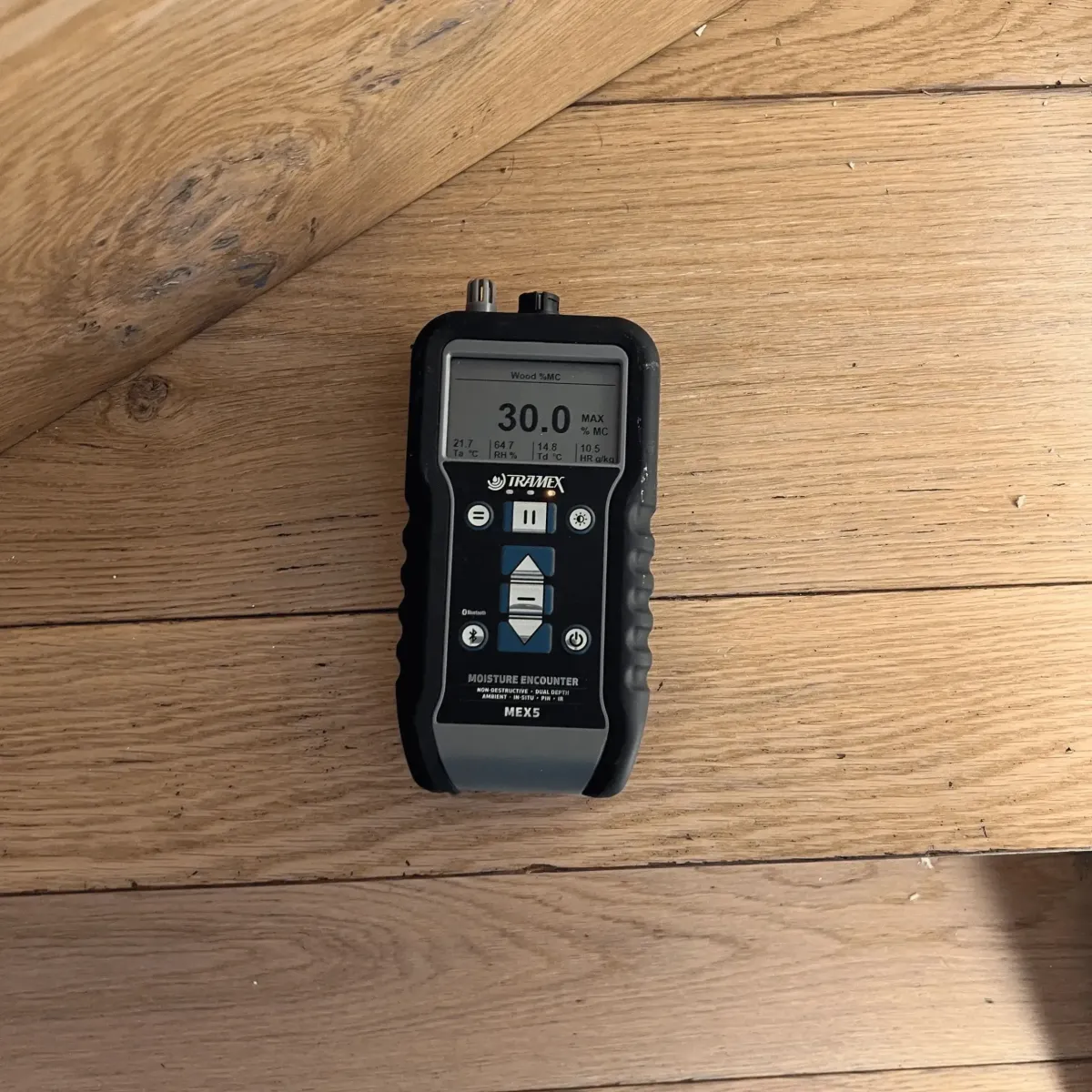 Moisture meter on timber floor measuring hidden water damage levels.