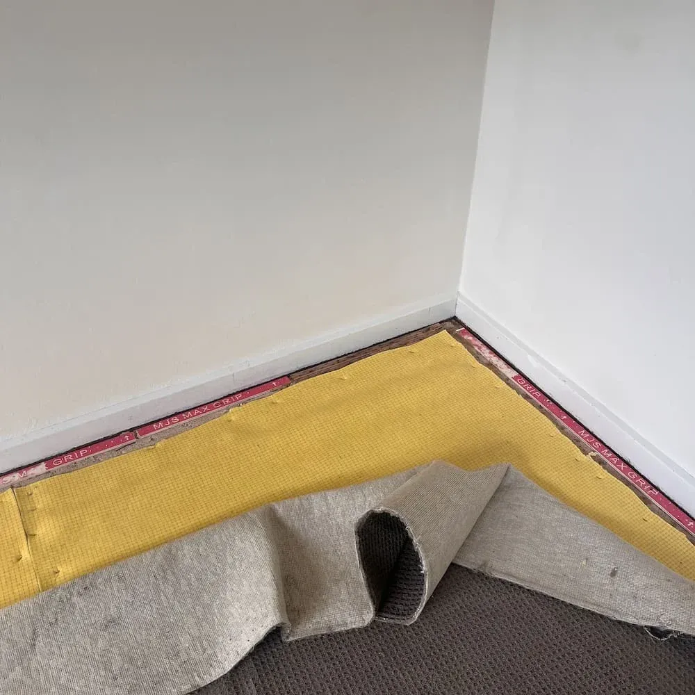 Exposed carpet underlay being replaced after water damage repair.