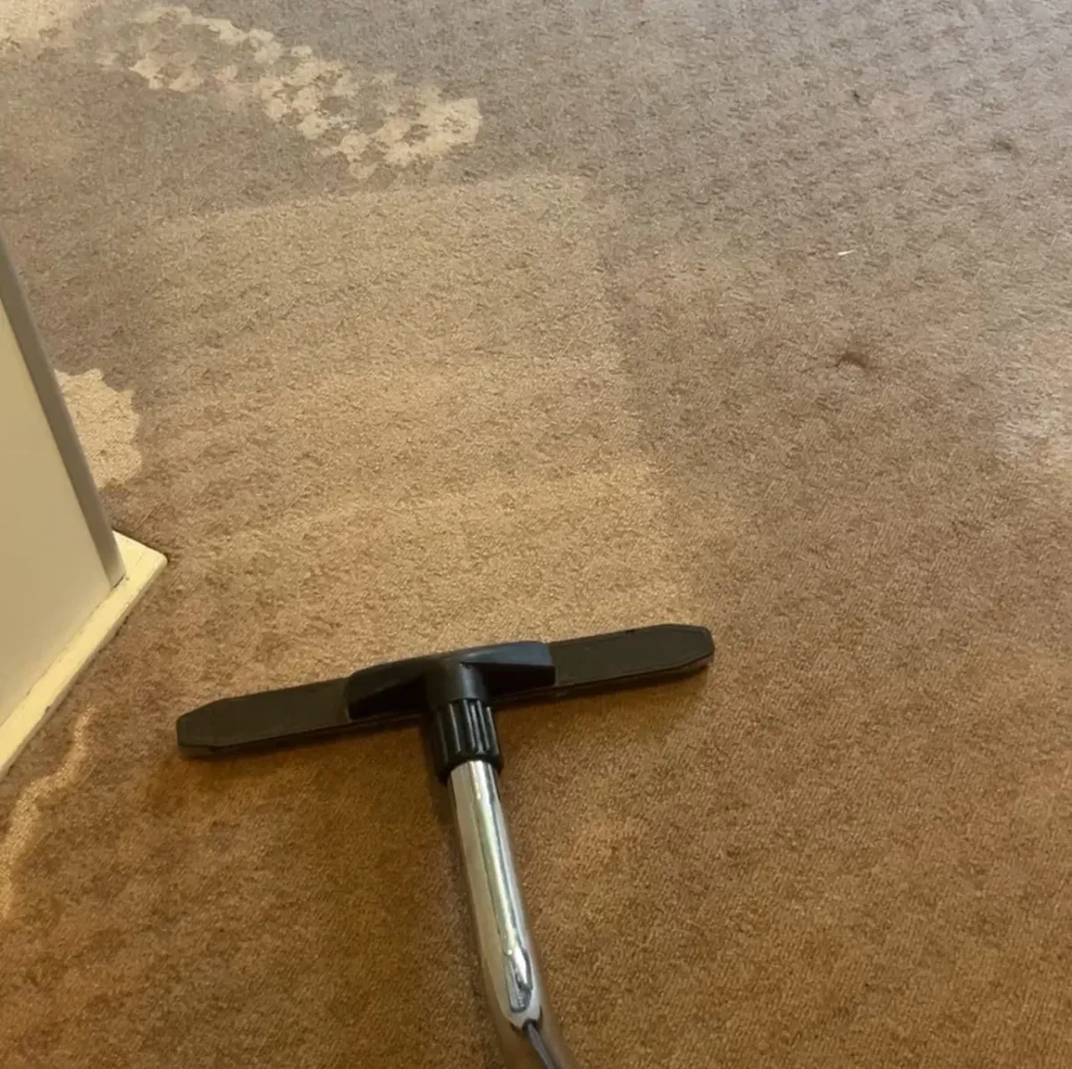 Water extraction vacuum removing moisture from wet carpet flooring.