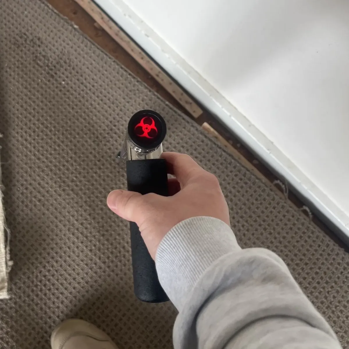 Technician using handheld moisture meter to assess damp carpet area.