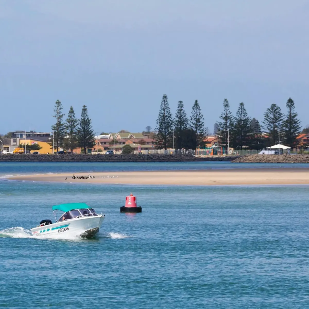 Boat cruising across Wollongong’s calm waters, highlighting the coastal communities served by High Demand Restoration for emergency water damage and mould remediation.