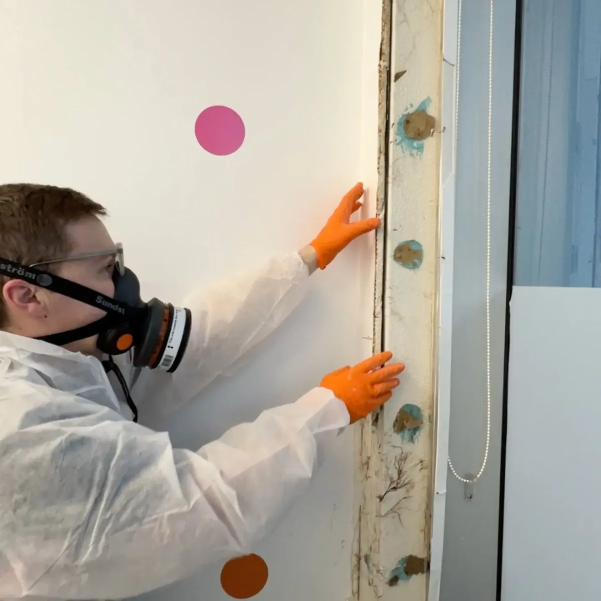 Technician in full protective gear inspecting a wall cavity for mould growth, showcasing High Demand Restoration’s expert mould inspection and assessment services in Sydney.