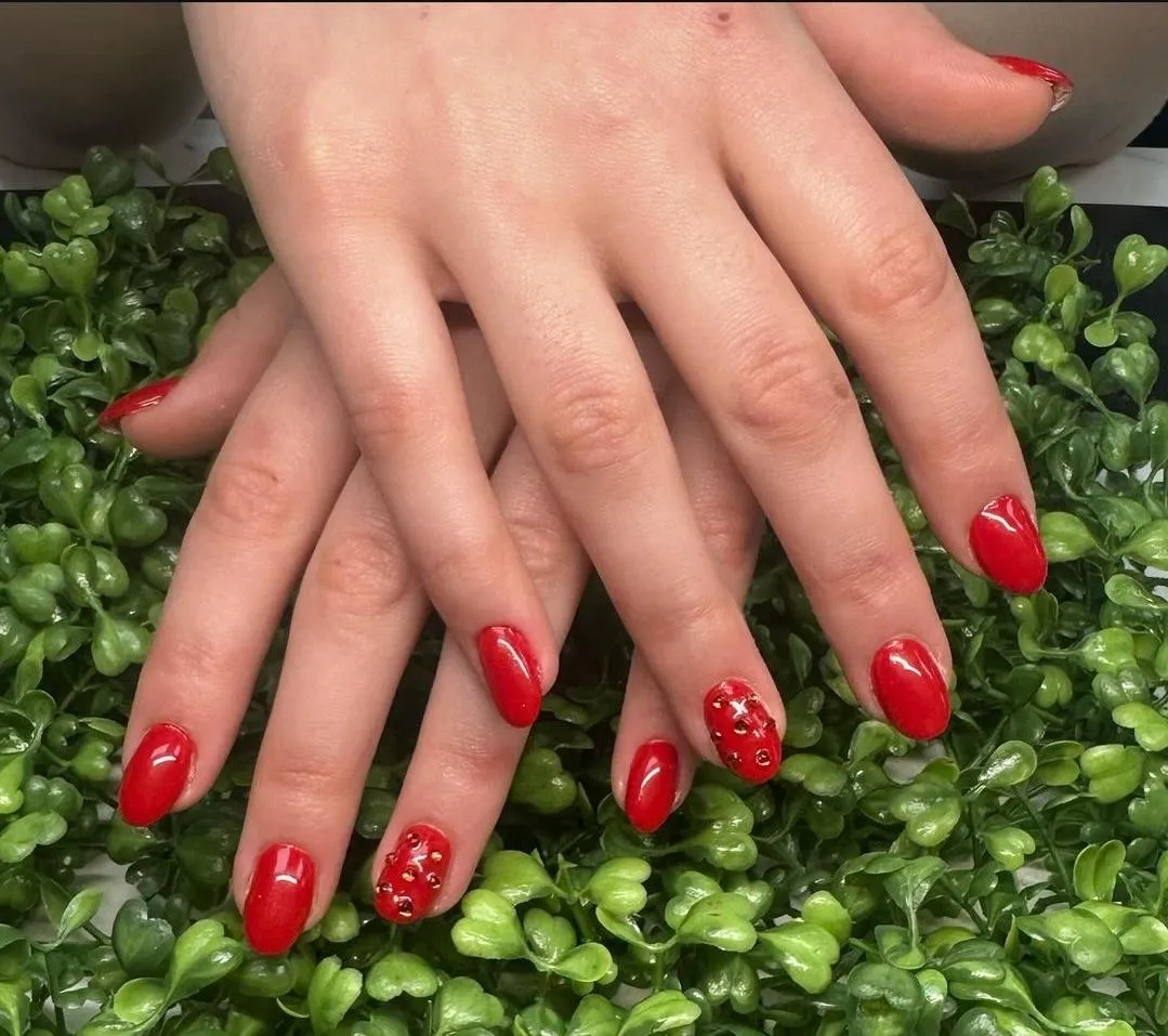 a set of red nails one nail on each hand has gems