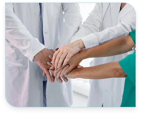 Group of medical professionals stacking hands to show unity and support in a healthcare setting.