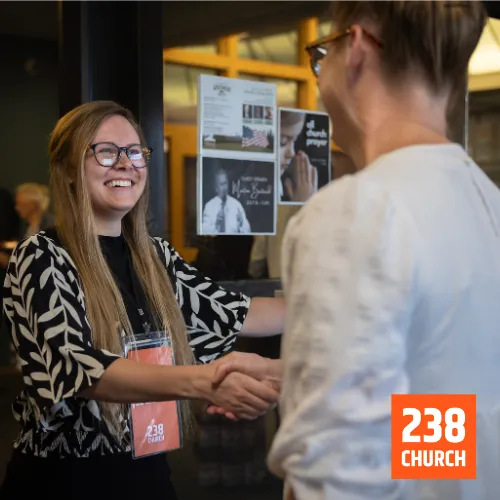 Welcoming greeter shaking hands at 238 Church in DeForest, fostering a friendly community atmosphere.