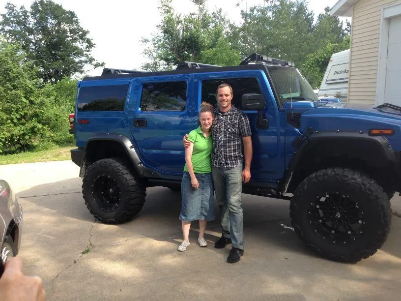 Pastor Jerry Simmons and his wife Lindsay standing beside a blue Hummer near 238 Church in DeForest, Wisconsin. 