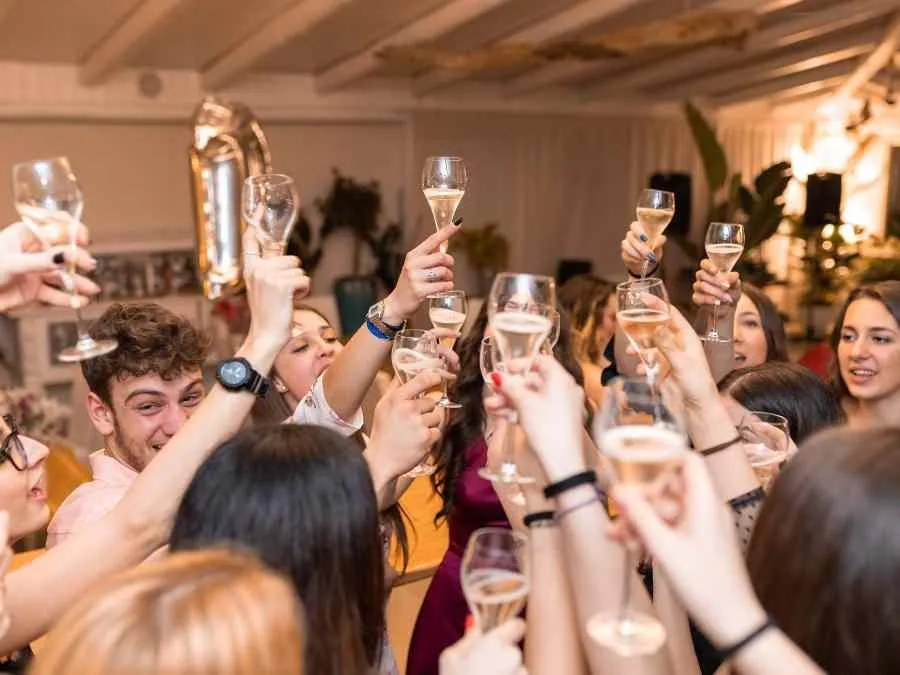 A wedding celebration with guests raising their champagne glasses on the dance floor