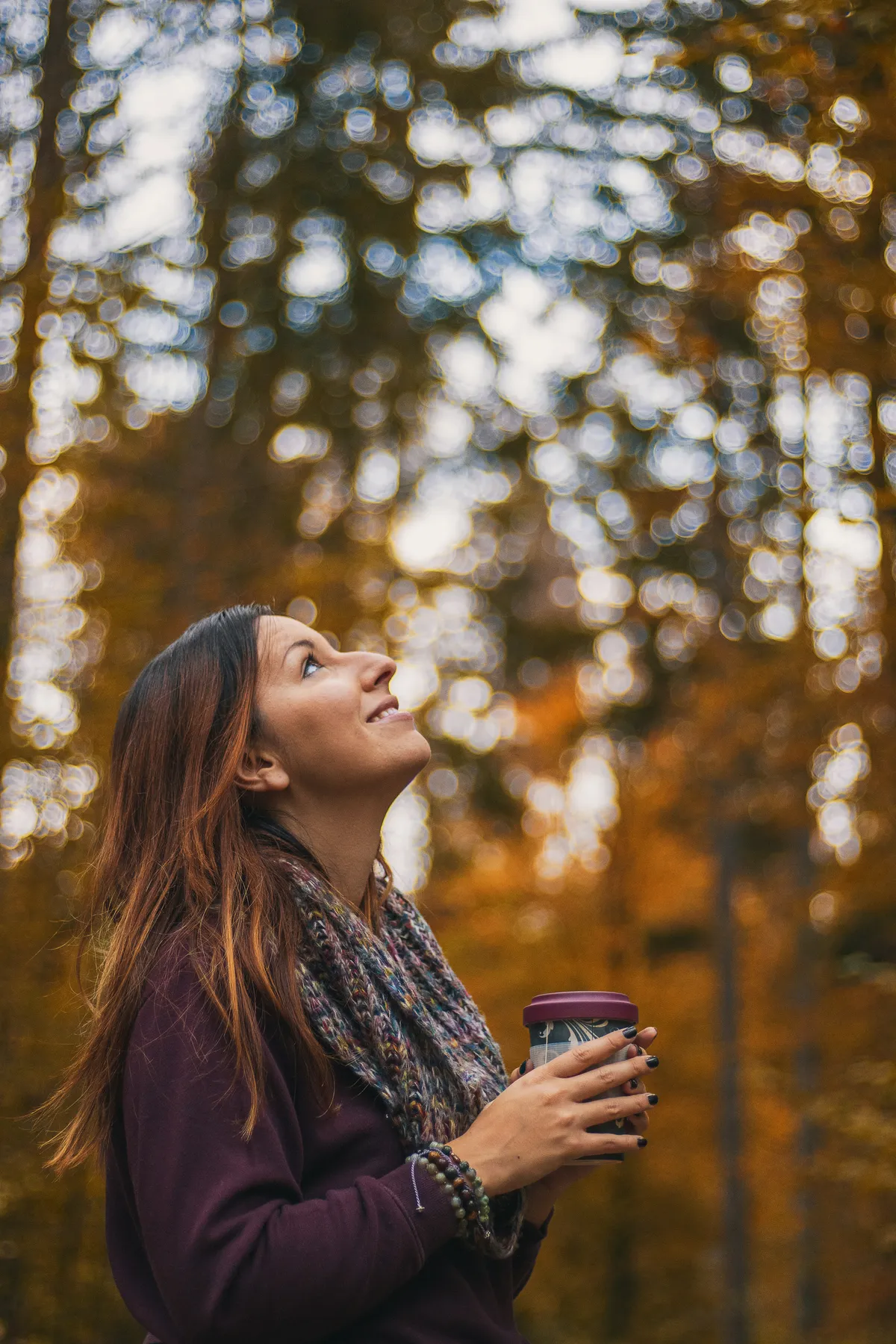 Woman standing peacefully in autumn forest clearing with warm ceramic mug reflecting mindfulness at Inhabit Retreat
