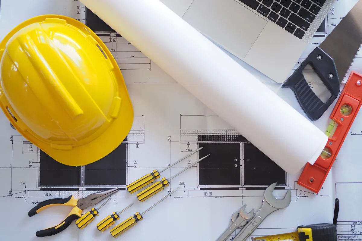 General contractor tools, blueprints, a hard hat and a laptop representing Ignite Solutions marketing services for general contractors