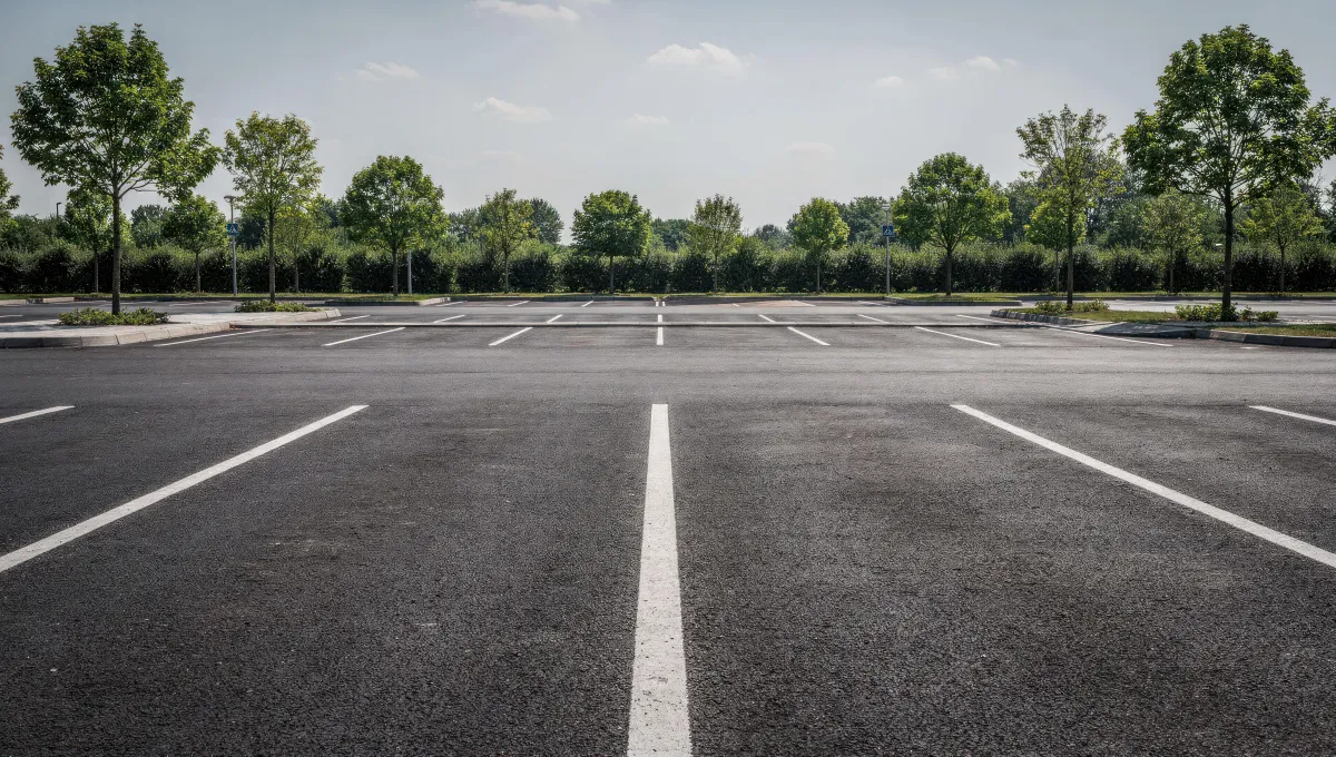 Freshly seal-coated commercial asphalt parking lot with crisp white line striping and smooth black pavement surface.