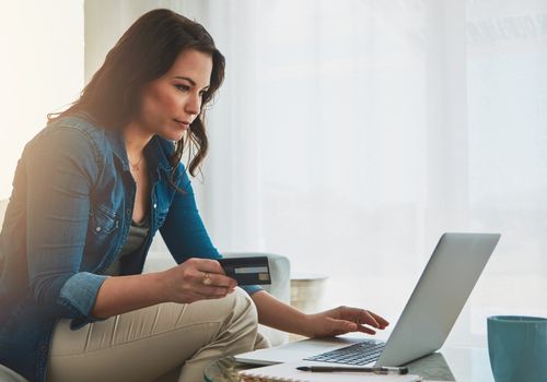 Woman paying off debt with credit card on laptop