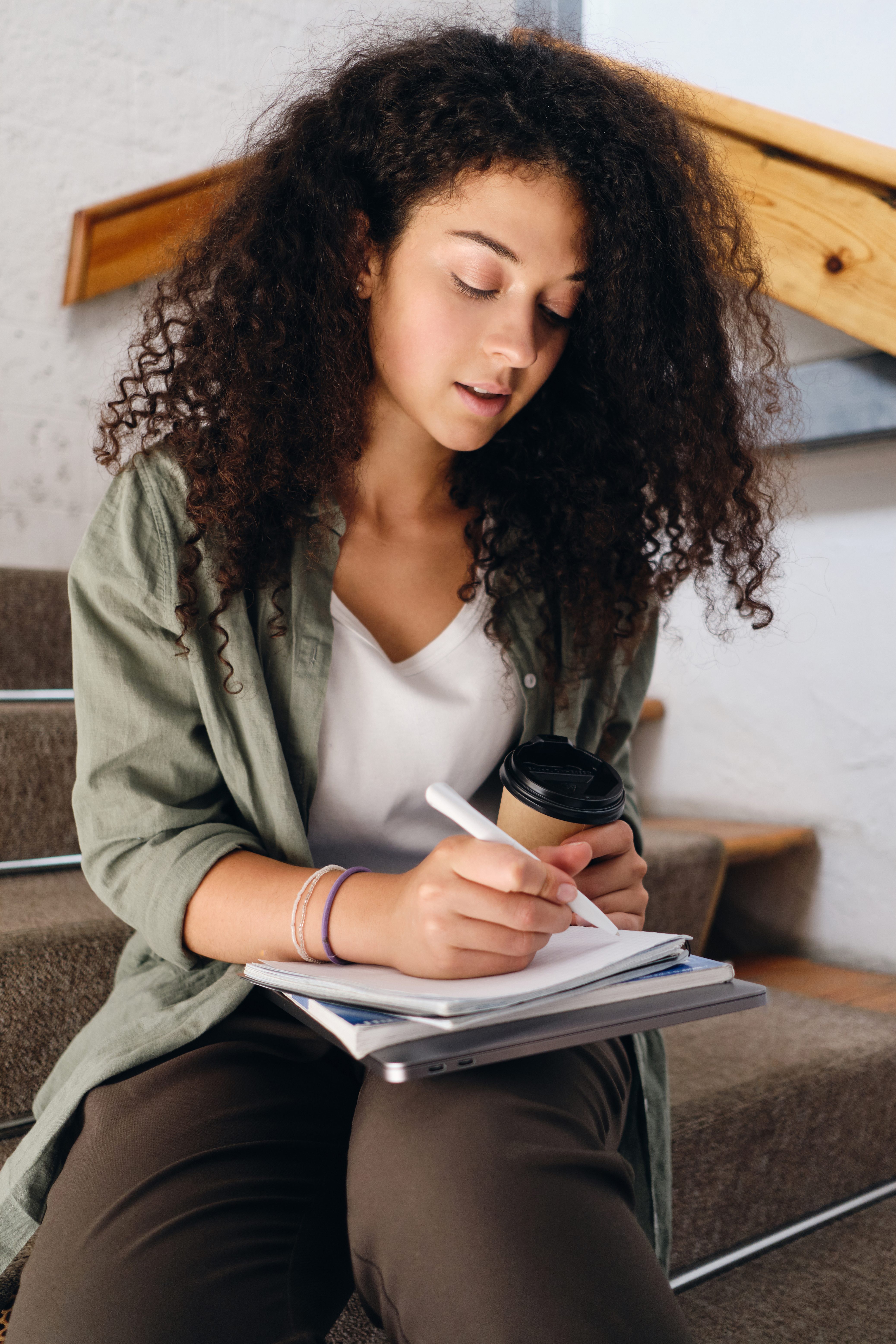 woman on stairs with notebook and coffee
