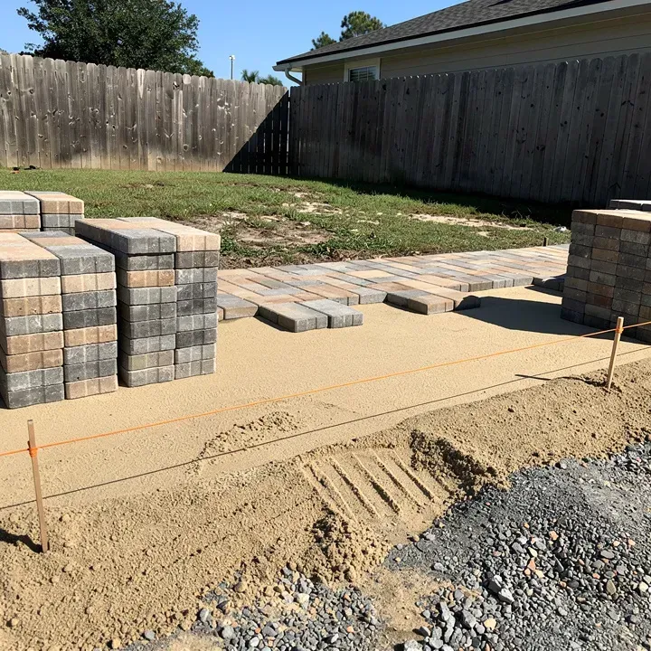 Paver installation in progress showing gravel base, sand leveling, and stacked paver stones