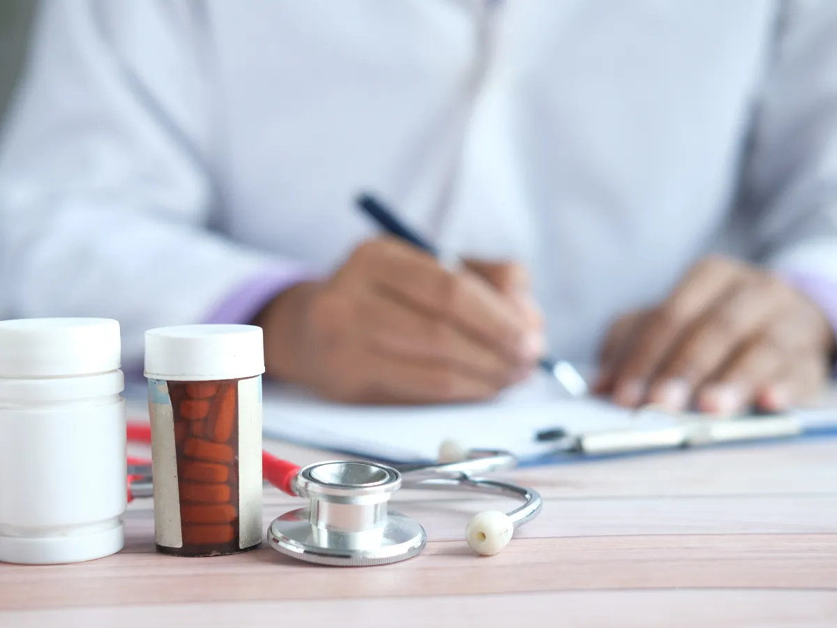 A pharmacist sitting at his desk with some pill bottles in front of him