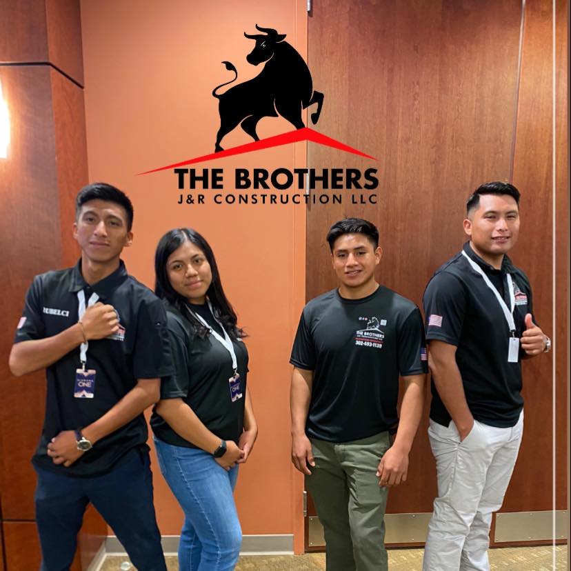 The Brothers JyR Construction LLC team standing in front of company logo in Lewes Delaware