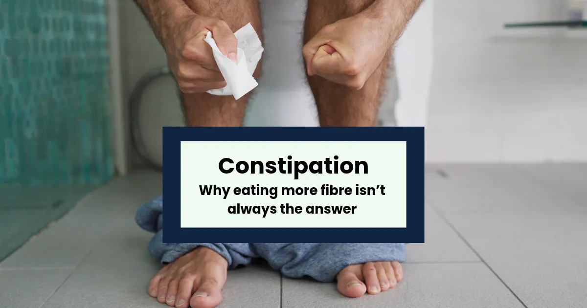 person clenching fists and squeezing toilet roll with trousers by ankles on the toilet, suggesting constipation