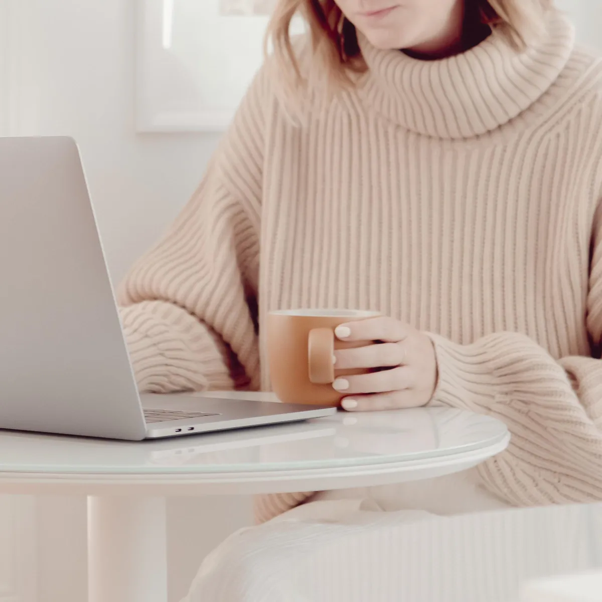 Woman working on laptop with coffee at home