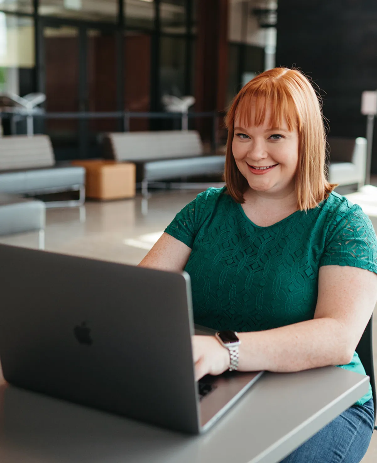 red hair woman sitting at laptop smiling