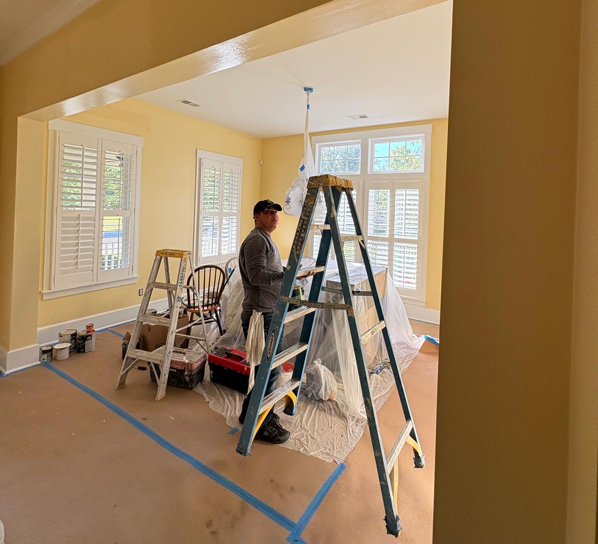 Interior painting prep with covered furniture, taped floors, and protected surfaces in a Summerville SC home