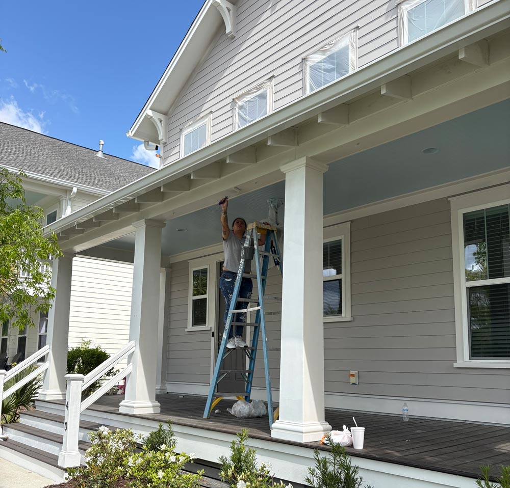 Painter working on exterior porch trim and ceiling details on a residential home in Summerville SC