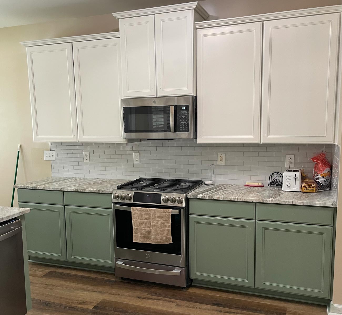 Freshly painted kitchen cabinets with white uppers and green lower cabinets in a residential kitchen