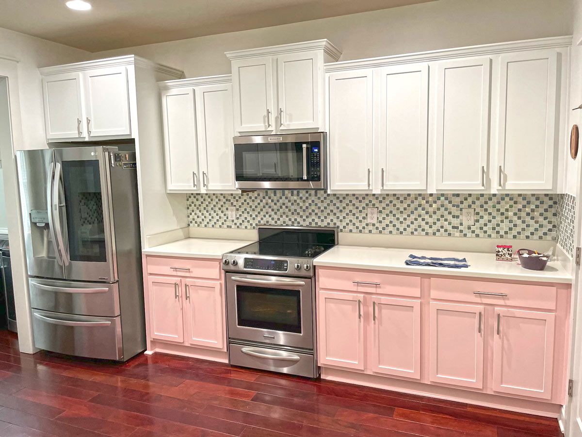 Kitchen with white upper cabinets and pink lower cabinets finished with standard cabinet painting by Camellia Painting Company