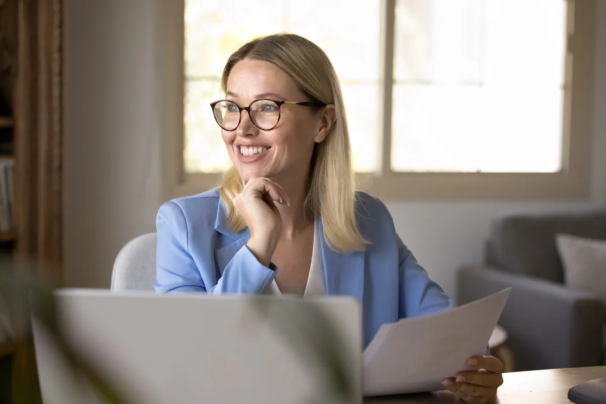 Confident woman smiling on laptop looking away.