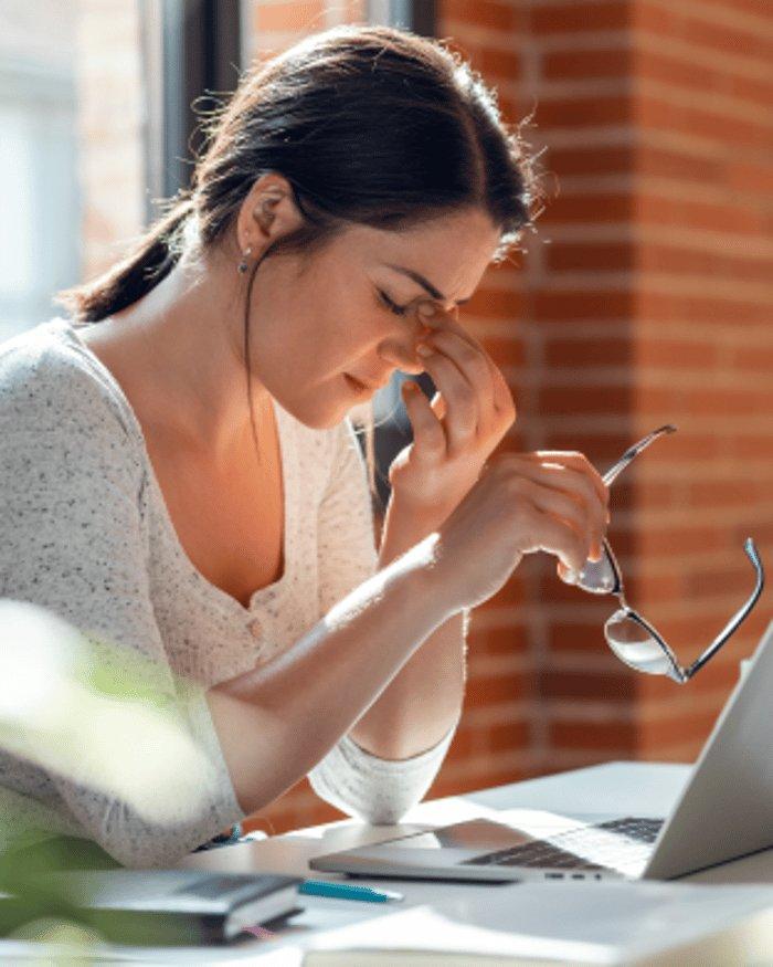 Woman lying down on a sofa, eyes closed, resting her hand on her forehead, appearing unwell or tired.