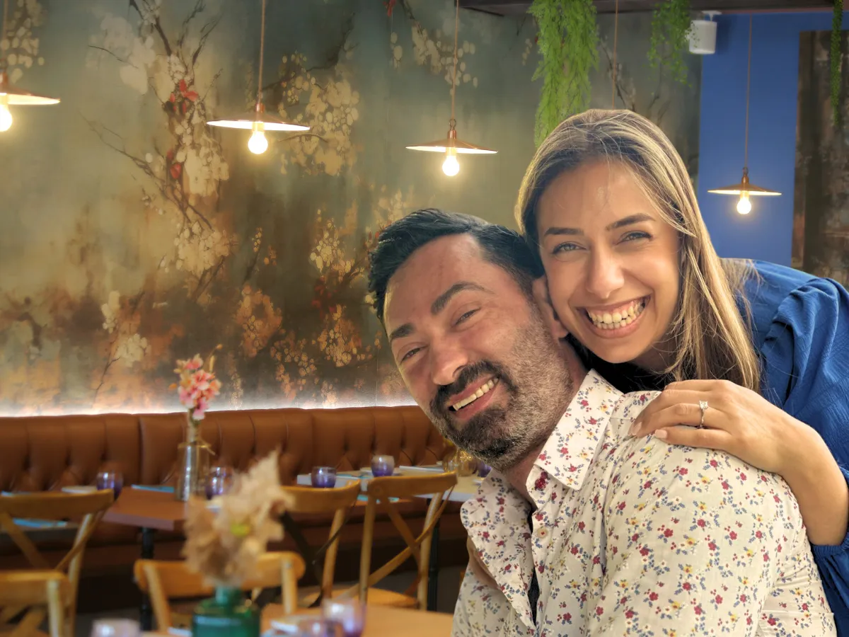 A chef in crisp white attire expertly garnishing a vibrant plate of handmade pasta, set against a dramatic all-black restaurant interior with golden accents, exuding luxury and authenticity. The chef's focused expression and the rich colors of the dish create an inviting, high-end atmosphere.