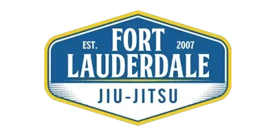 Young student smiling while receiving her belt from a coach at Fort Lauderdale Jiu-Jitsu kids program